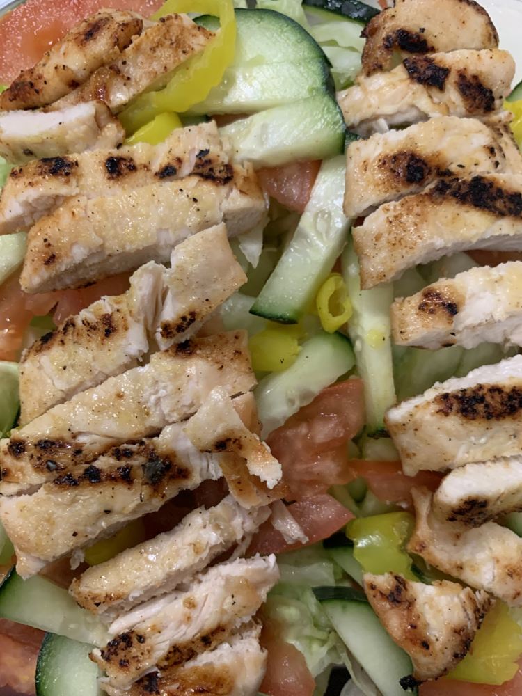 Sliced grilled chicken on a fresh vegetable salad