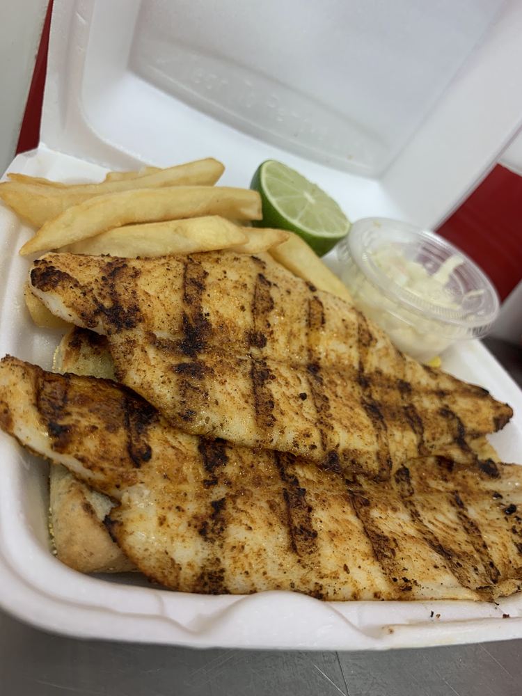 Grilled fish with fries, lemon and a side of coleslaw